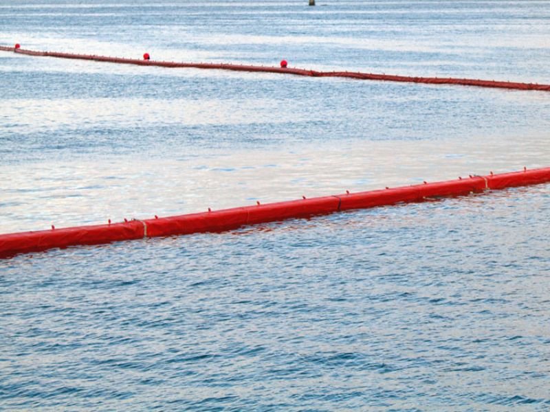Offshore oil booms isolating oil slick to prevent environmental damage